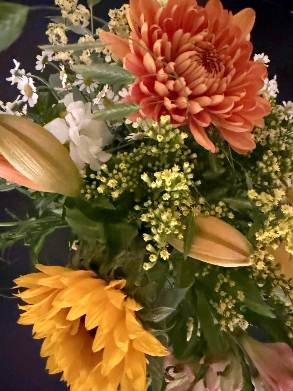 Buket med orange krysantemum, solsikke og liljer fra receptionen